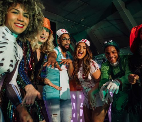 A group of young friends wearing fancy dress costumes on a night out during halloween, dancing in a nightclub in Newcastle, North East England. They are all having fun while pulling different poses and looking at the camera.